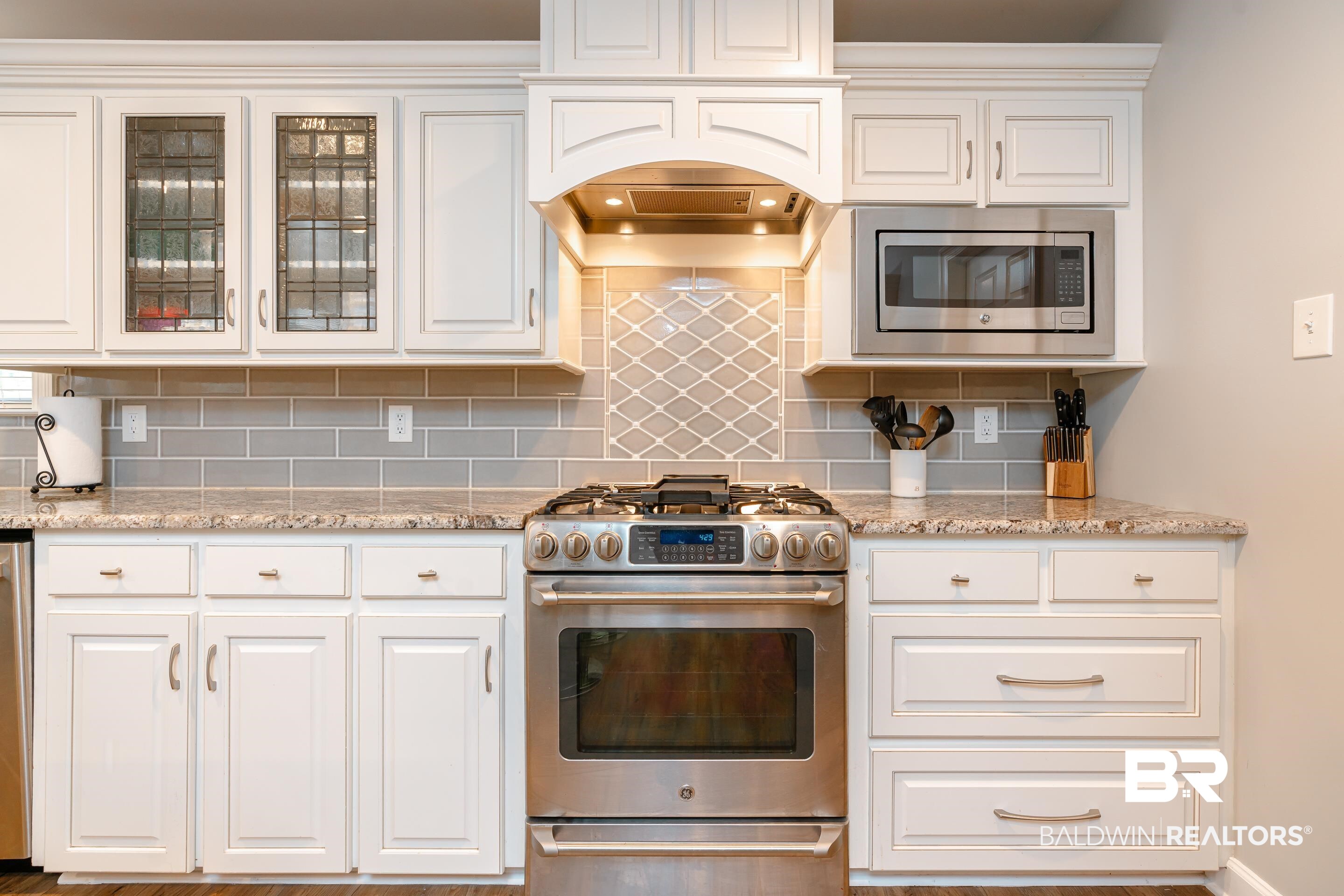 9477 Deerfield Drive Irvington, AL 36544 - Photo 12 of 58 Kitchen with appliances with stainless steel finishes, light stone counters, backsplash, and white cabinets
