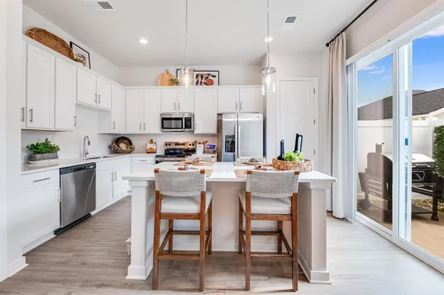 a kitchen with stainless steel appliances kitchen island granite countertop a table chairs and a refrigerator