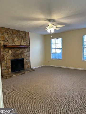 an empty room with a chandelier fan and windows