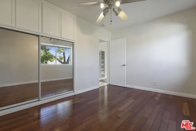 an empty room with wooden floor chandelier fan and windows