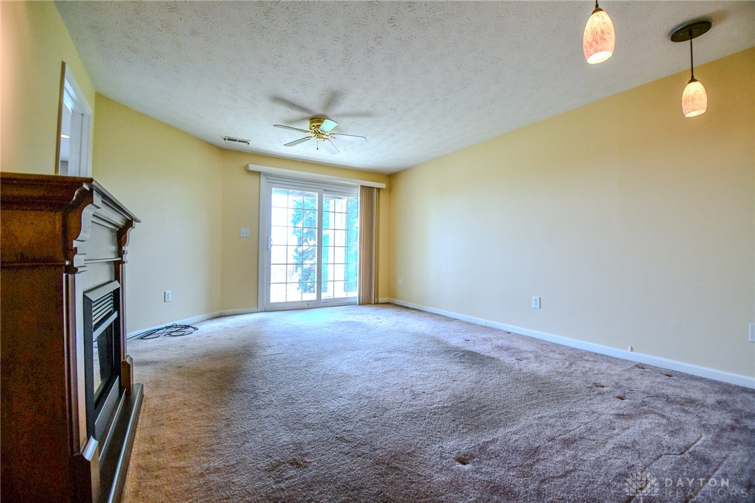 3915 East Summit Ridge Drive Beavercreek, OH 45430 - Photo 33 of 47 This living room features soft carpeting and a fireplace, offering a cozy retreat with outdoor access.