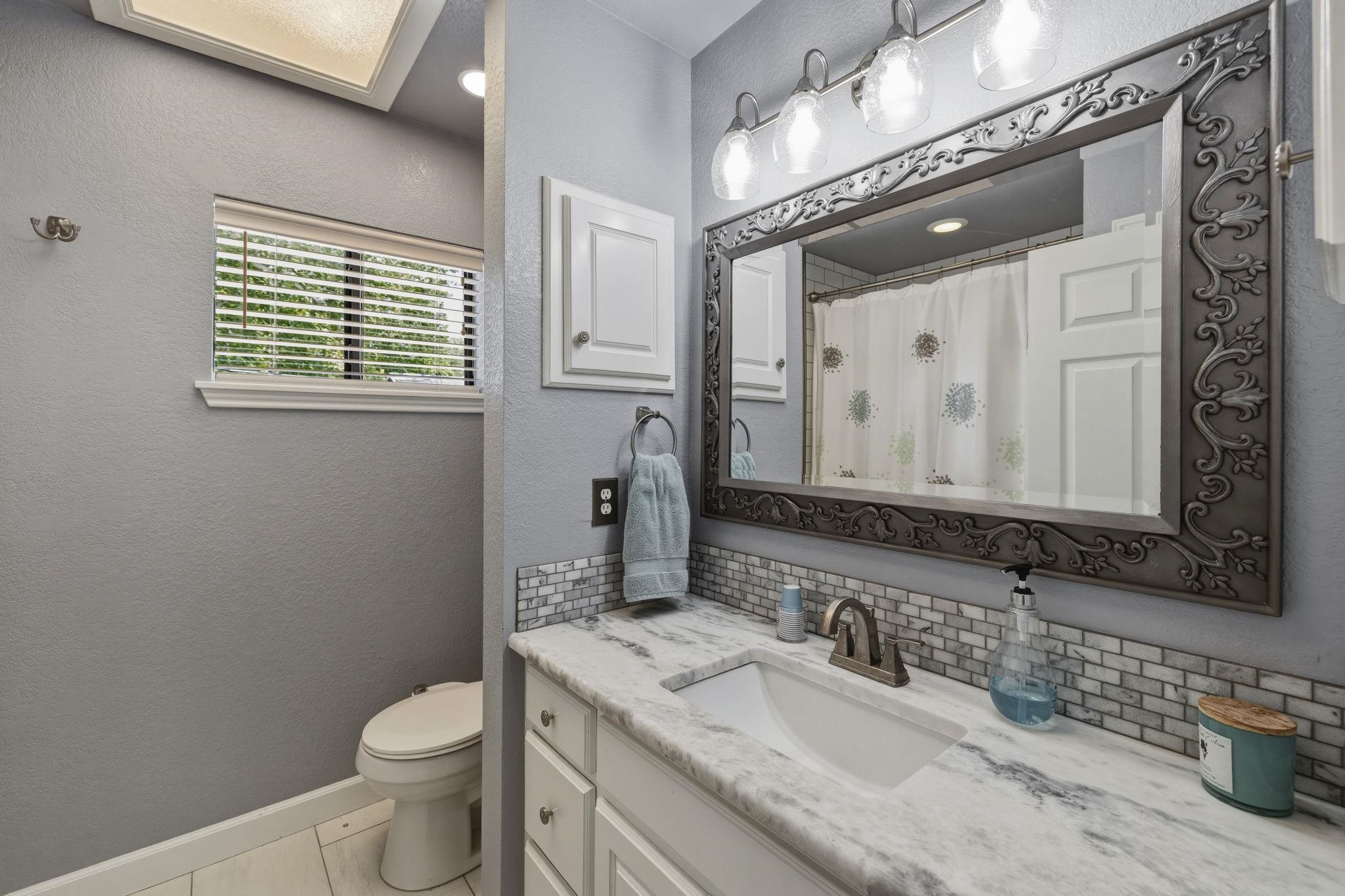 1435 East Zipp Road New Braunfels, TX 78130 - Photo 36 of 43 a bathroom with a granite countertop toilet a sink and a mirror