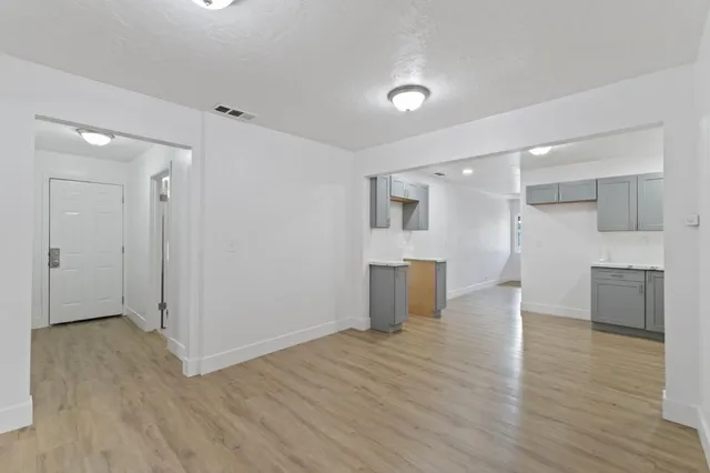 a view of a big room with wooden floor and a kitchen