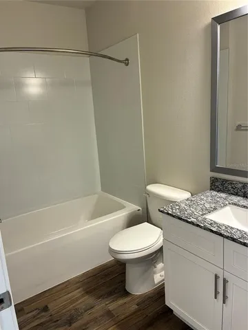 a bathroom with a granite countertop bathtub shower sink vanity and toilet