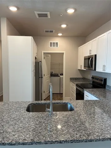 a kitchen with kitchen island granite countertop a refrigerator and a sink