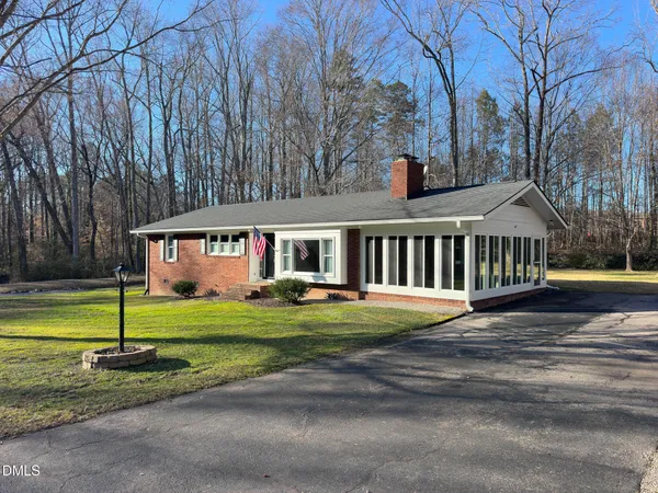 a view of a house with a big yard and large trees