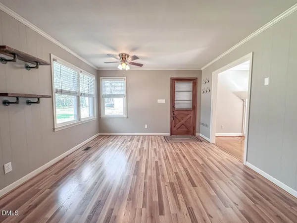 a view of an empty room with a window and wooden floor
