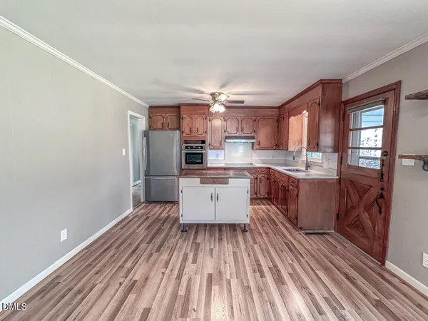 a kitchen with stainless steel appliances a refrigerator a sink dishwasher with a dining table and chairs