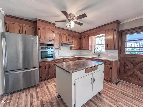 a kitchen with stainless steel appliances granite countertop a refrigerator a sink dishwasher a stove and white countertops with wooden floor