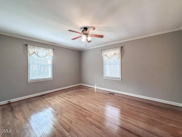 a view of an empty room with a window and wooden floor