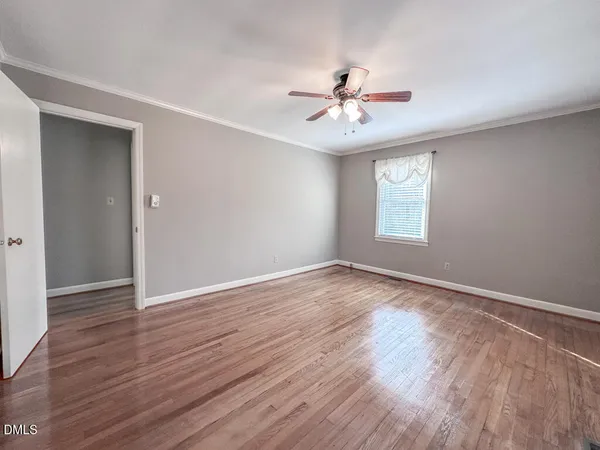 an empty room with wooden floor fan and windows