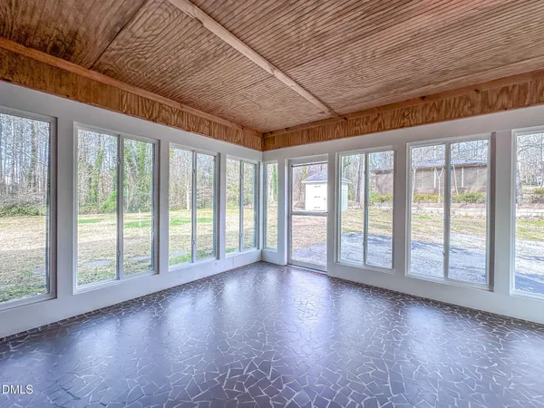 a view of an empty room with wooden floor and a floor to ceiling window