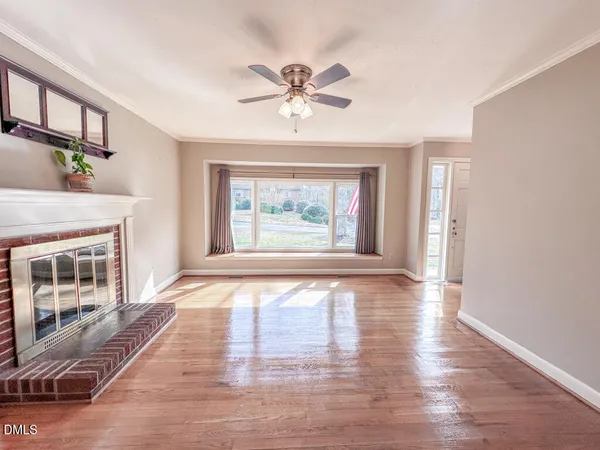 a view of an empty room with window and wooden floor