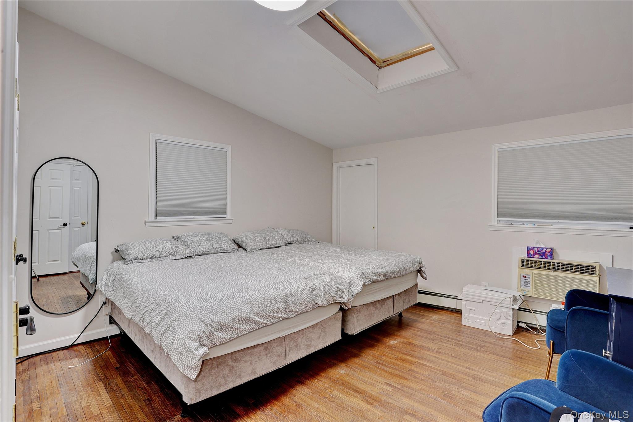 35 Regina Road Monsey, NY 10952 - Photo 14 of 34 Bedroom featuring lofted ceiling, light wood-style floors, baseboard heating, a wall mounted AC, and attic access