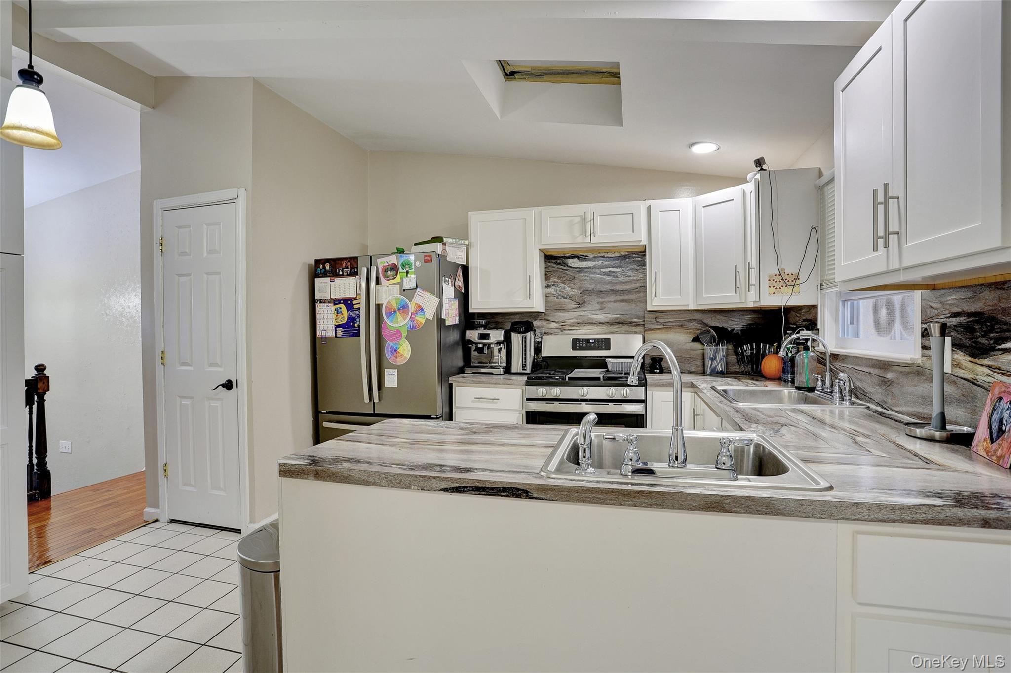 35 Regina Road Monsey, NY 10952 - Photo 10 of 34 Kitchen with vaulted ceiling, white cabinets, appliances with stainless steel finishes, backsplash, and light tile patterned floors