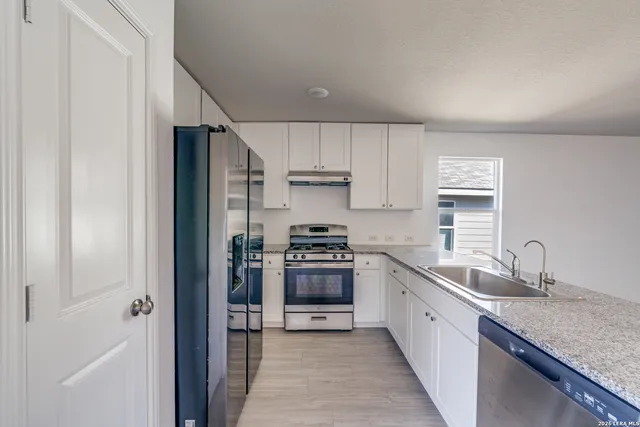 a kitchen with stainless steel appliances granite countertop a sink stove and refrigerator