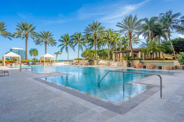 a row of palm trees and swimming pool in the backyard of a house