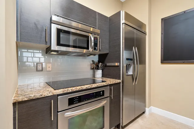 a kitchen with stainless steel appliances granite countertop a sink refrigerator and microwave