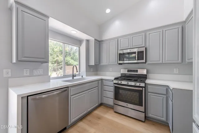 a kitchen with sink a microwave a stove and cabinets