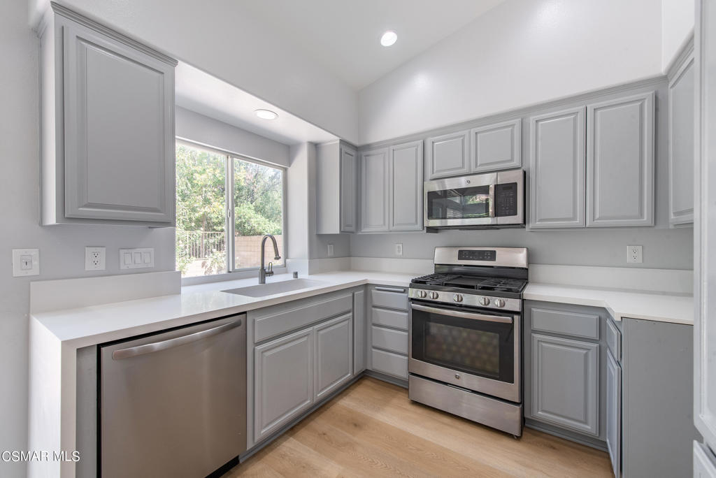 4774 Rhapsody Drive Oak Park, CA 91377 - Photo 8 of 34 a kitchen with sink a microwave a stove and cabinets