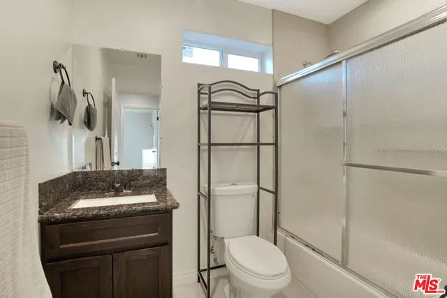 a bathroom with a granite countertop sink toilet and shower