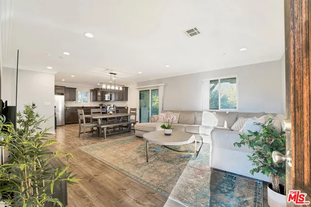 a living room with furniture and potted plants with kitchen view