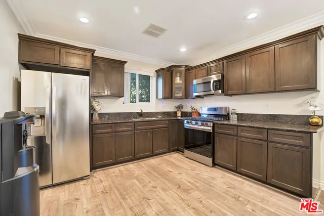 a kitchen with stainless steel appliances granite countertop a refrigerator stove top oven and sink