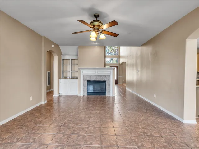 a view of an empty room with windows and chandelier fan