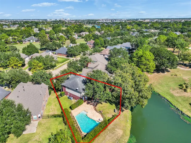an aerial view of a swimming pool with a yard and lake view