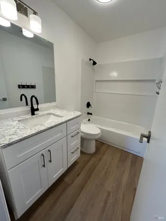 a bathroom with a granite countertop sink toilet and mirror
