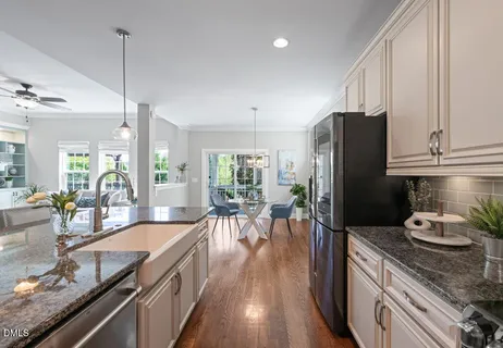 a kitchen with stainless steel appliances granite countertop a refrigerator a sink dishwasher a stove and white countertops with wooden floor