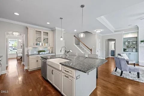 a kitchen with a counter top space a sink appliances and wooden floor