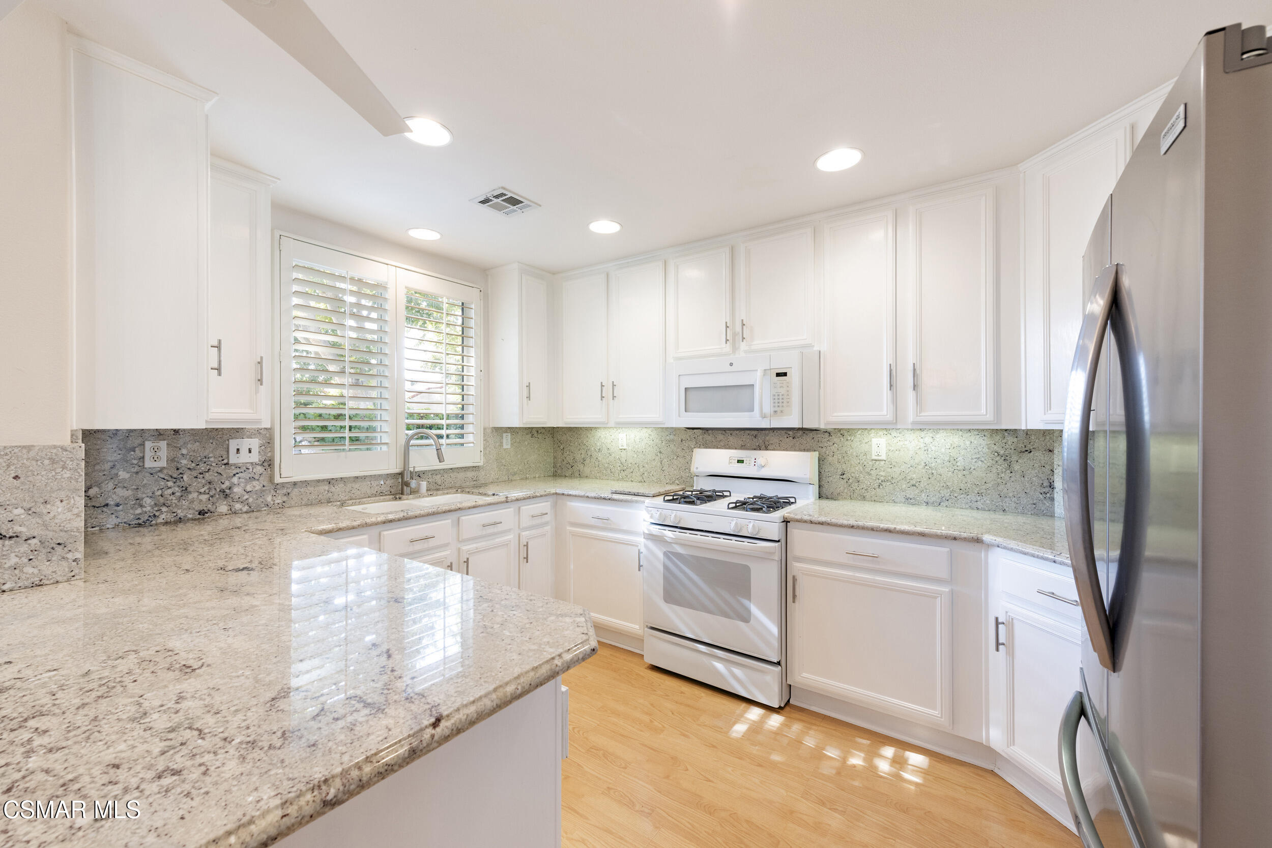 2059 Tulip Avenue Simi Valley, CA 93063 - Photo 11 of 37 a kitchen with stainless steel appliances granite countertop a sink a stove a refrigerator and a granite counter tops with white cabinets