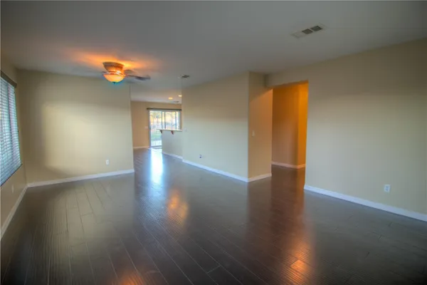 a view of an empty room with wooden floor and windows