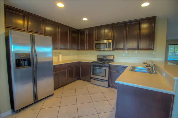 a kitchen with stainless steel appliances kitchen island granite countertop a refrigerator a stove and a sink