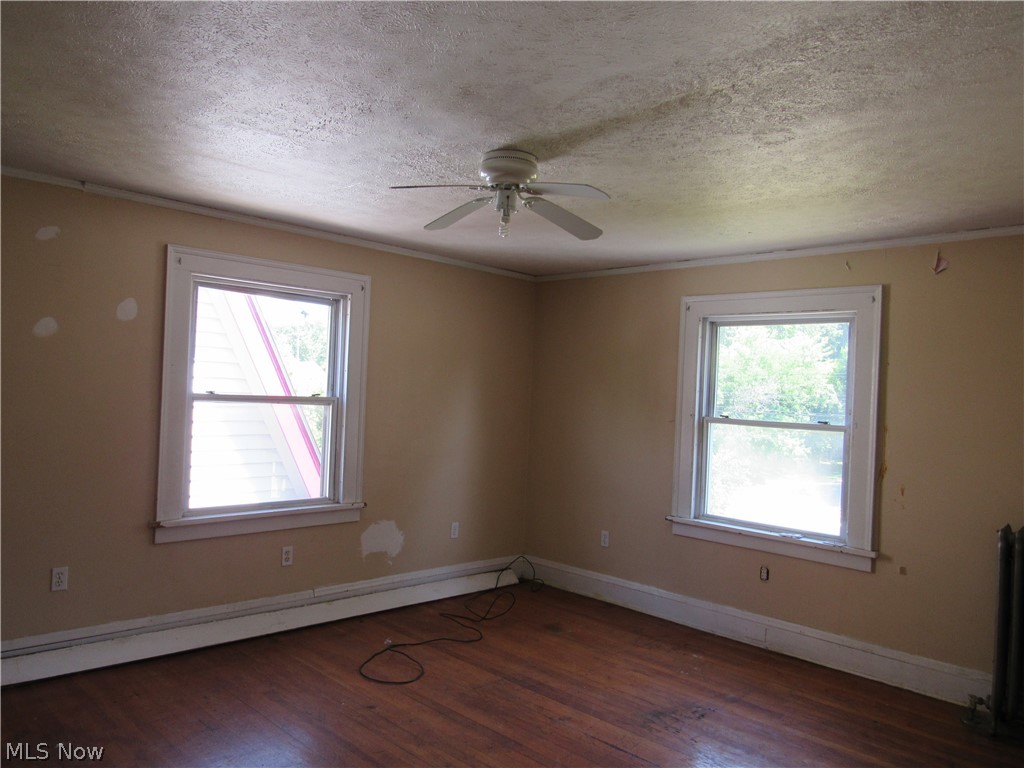 1726 Lee Road Cleveland Heights, OH 44118 - Photo 18 of 36 Room featuring wood-finish flooring, two windows with white trim, a ceiling fan, and baseboard heating
