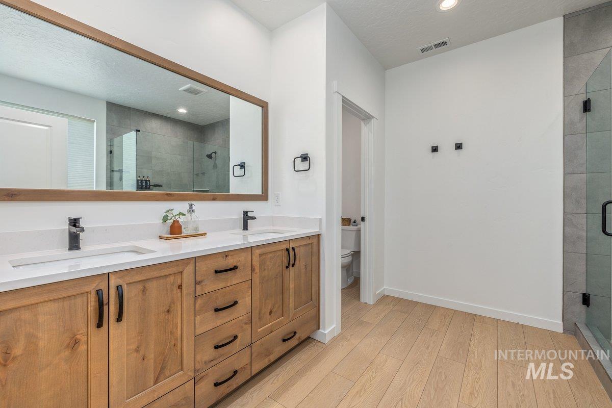 1380 West Chilitna Street Meridian, ID 83642 - Photo 29 of 50 Double vanity with light wood-finish cabinetry, white countertops, and matte black fixtures