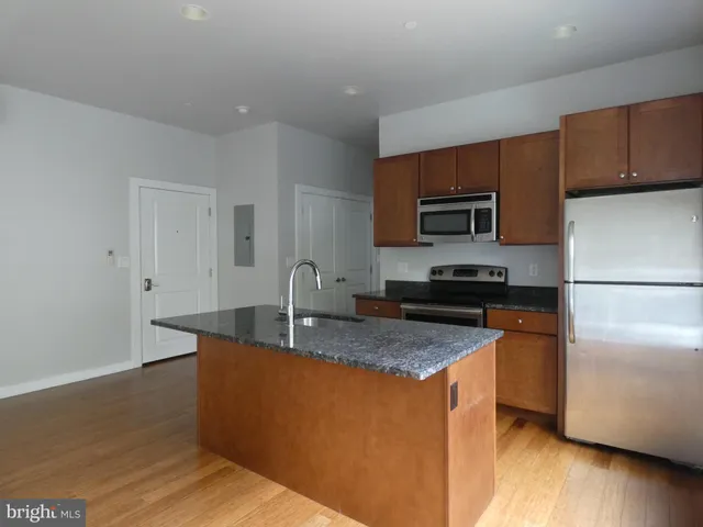 a kitchen with stainless steel appliances granite countertop a refrigerator a sink a stove a microwave and wooden cabinets