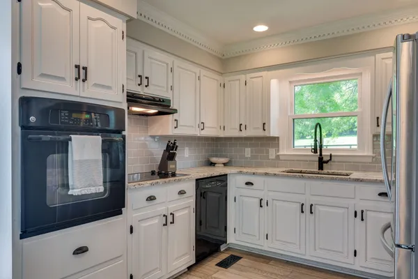 a kitchen with white cabinets and window