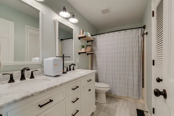 a bathroom with a granite countertop sink a toilet and shower