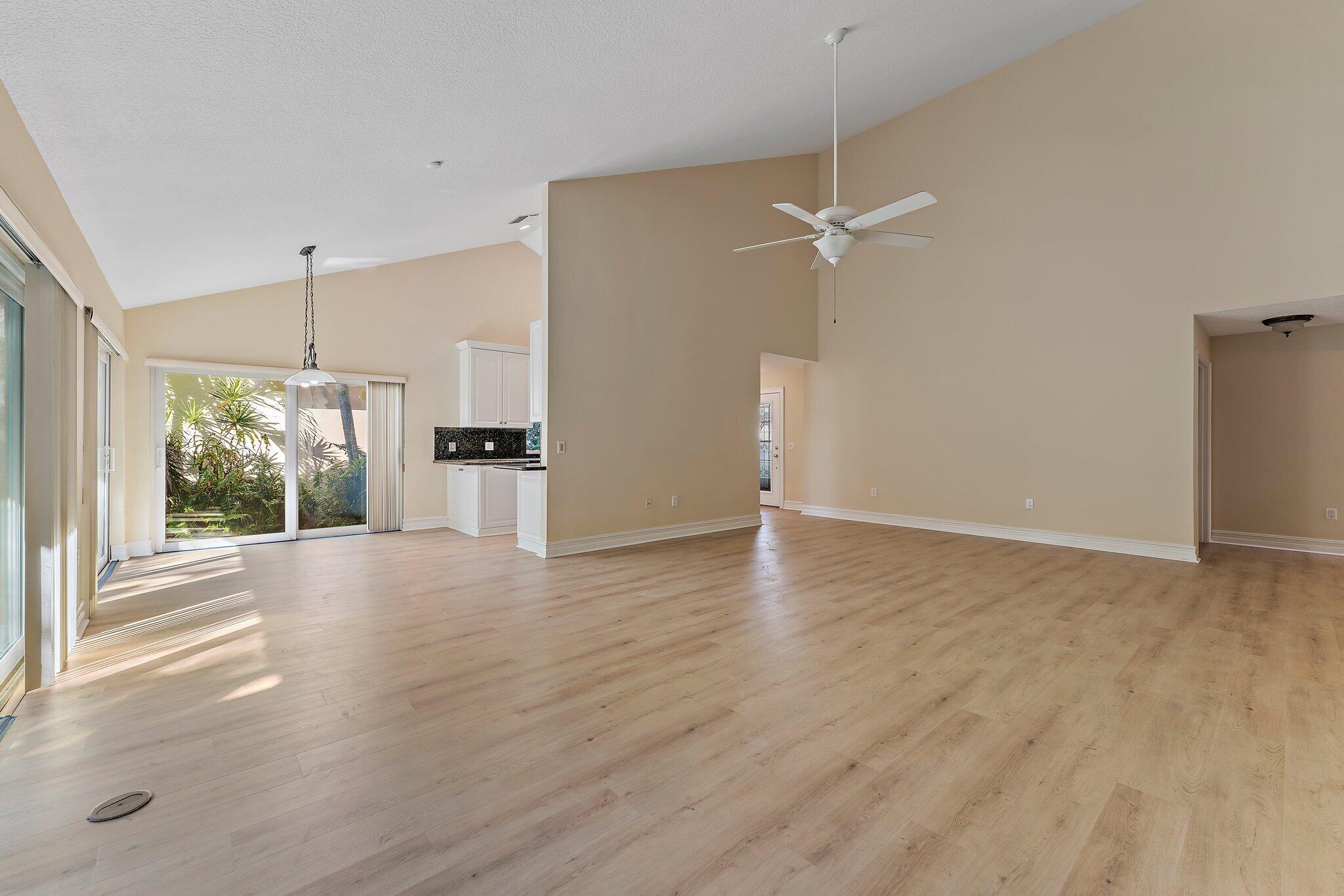 118 Knoll Way Jupiter, FL 33477 - Photo 14 of 40 an empty room with wooden floor ceiling fan and windows