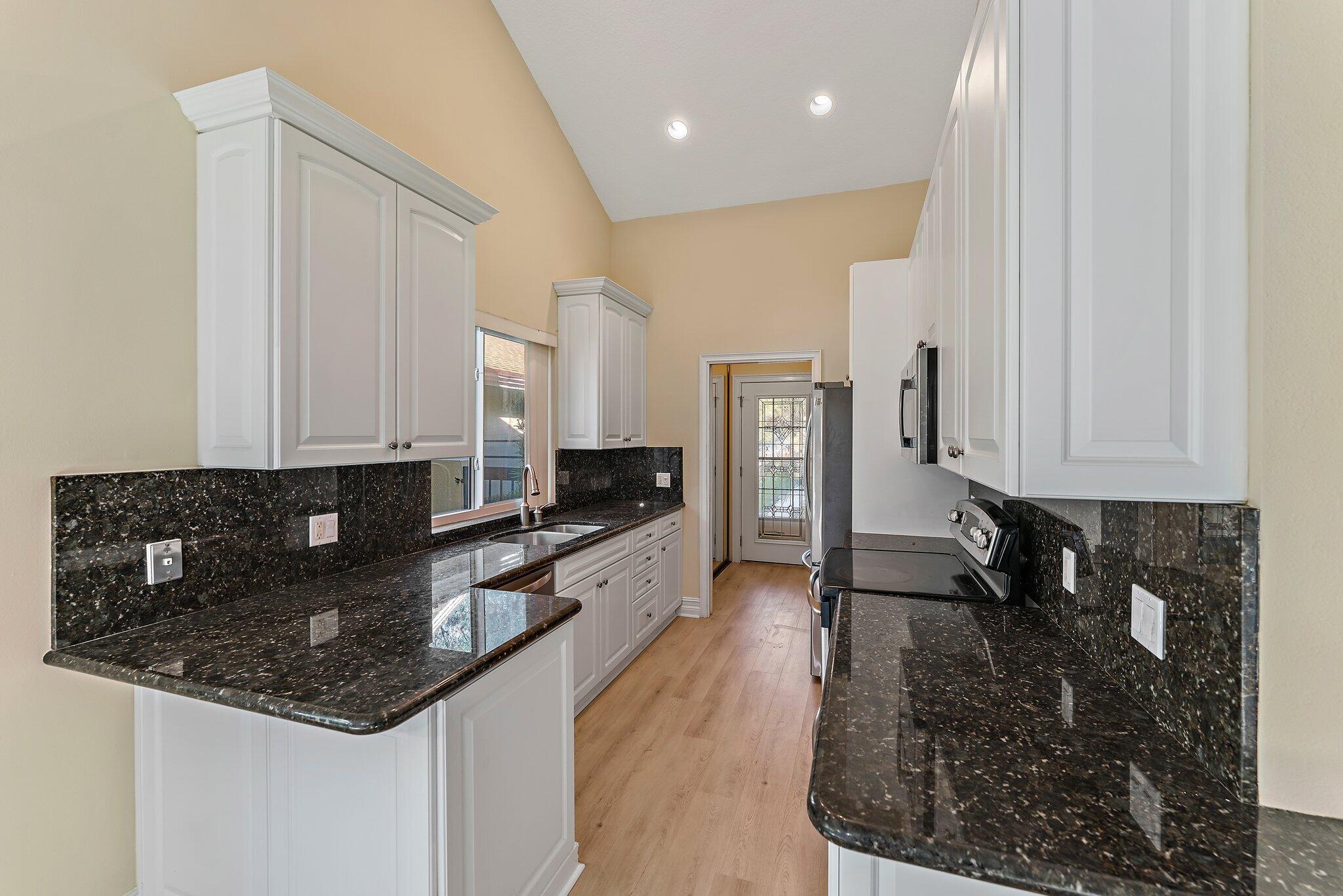 118 Knoll Way Jupiter, FL 33477 - Photo 21 of 40 a kitchen with granite countertop a sink a stove and cabinets