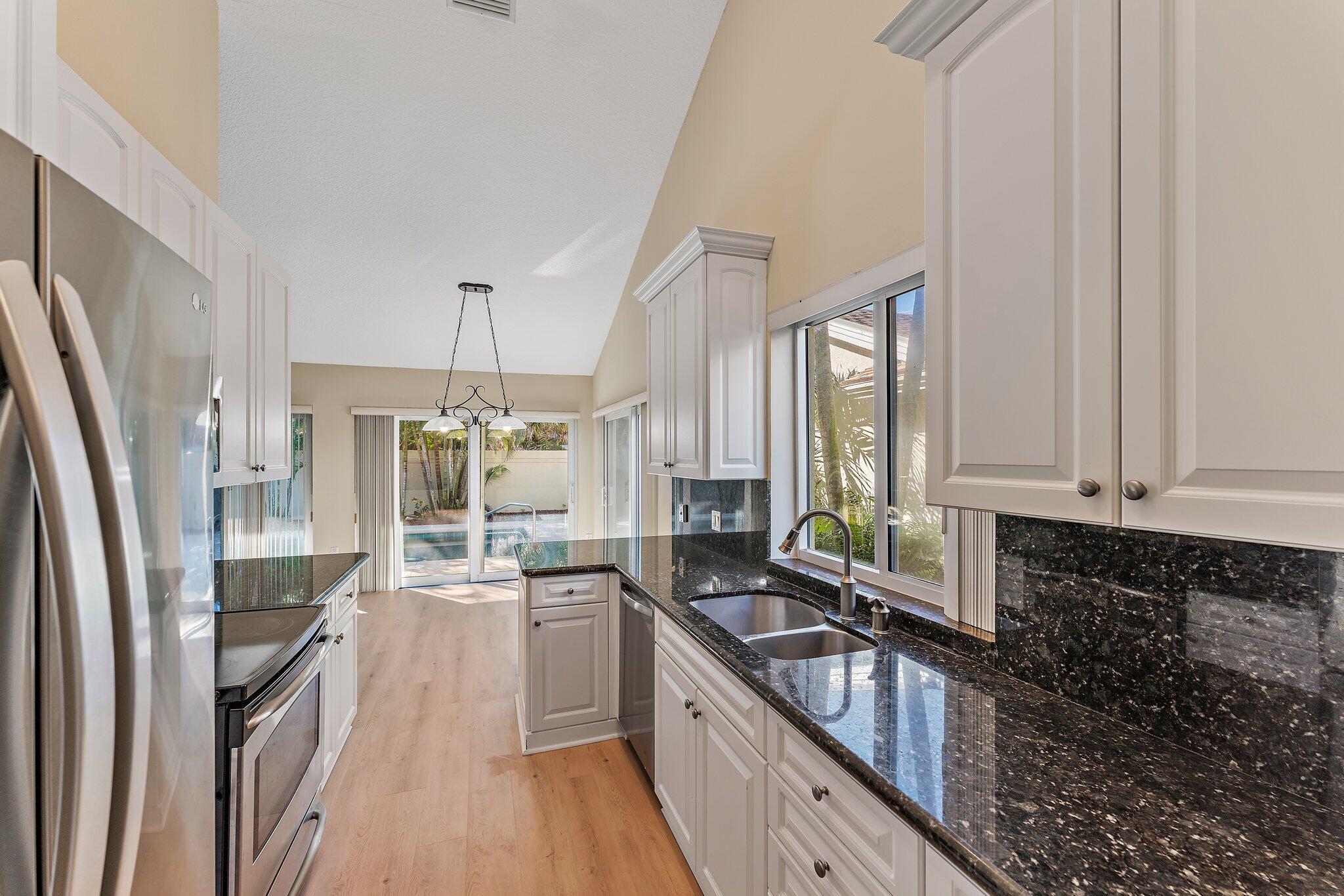 118 Knoll Way Jupiter, FL 33477 - Photo 23 of 40 a kitchen with stainless steel appliances granite countertop a refrigerator a sink dishwasher a stove and white countertops with wooden floor