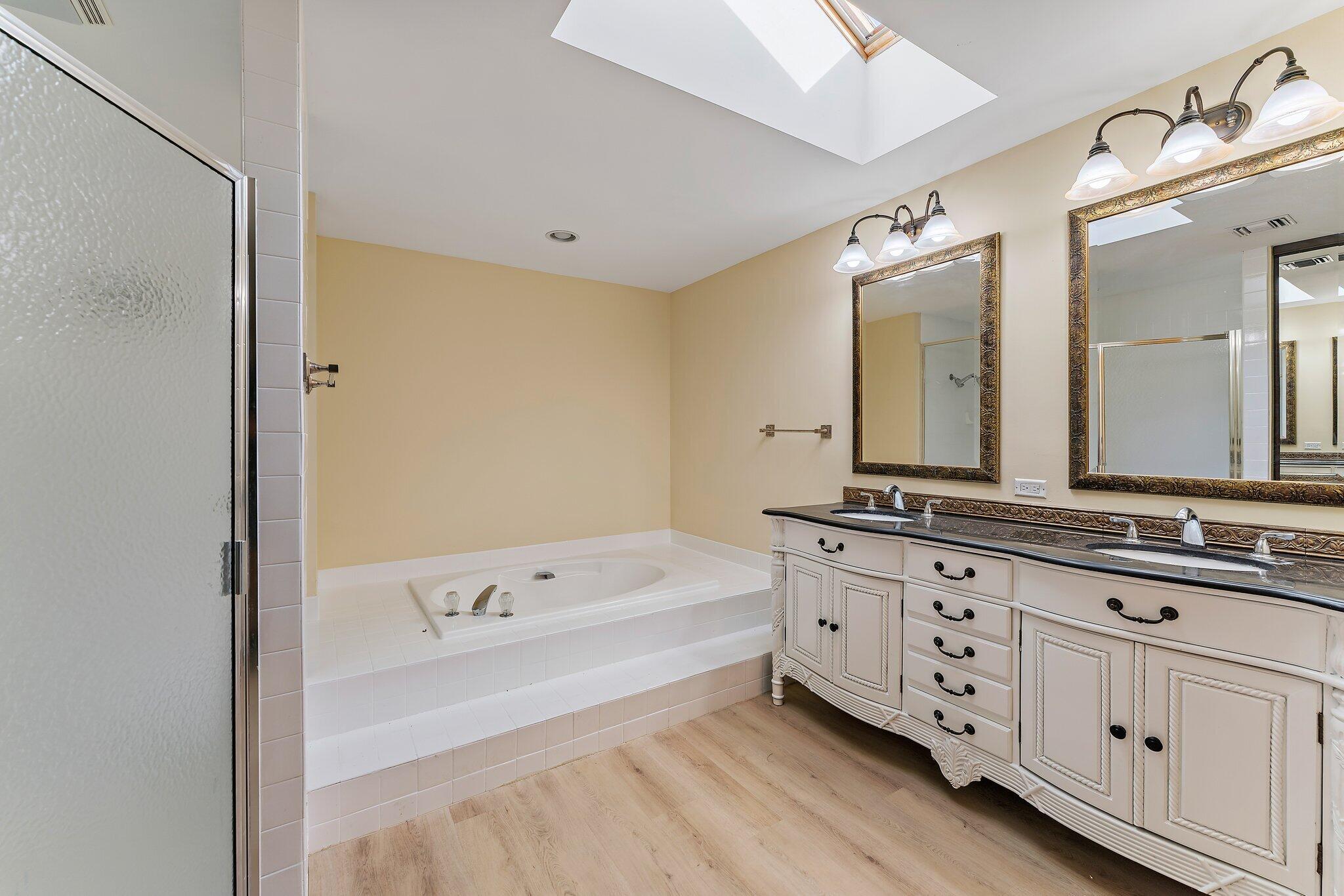 118 Knoll Way Jupiter, FL 33477 - Photo 29 of 40 a bathroom with a tub a double vanity sink and mirror