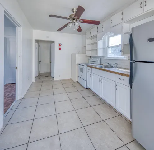 a large kitchen with a stove a faucet cabinets and a view of kitchen