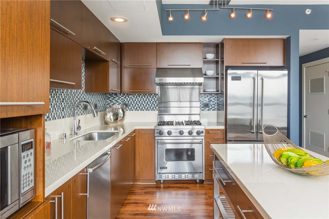2911 2nd Avenue, Unit 903 Seattle, WA 98121 - Photo 12 of 25 a kitchen with stainless steel appliances granite countertop a sink a stove and a refrigerator