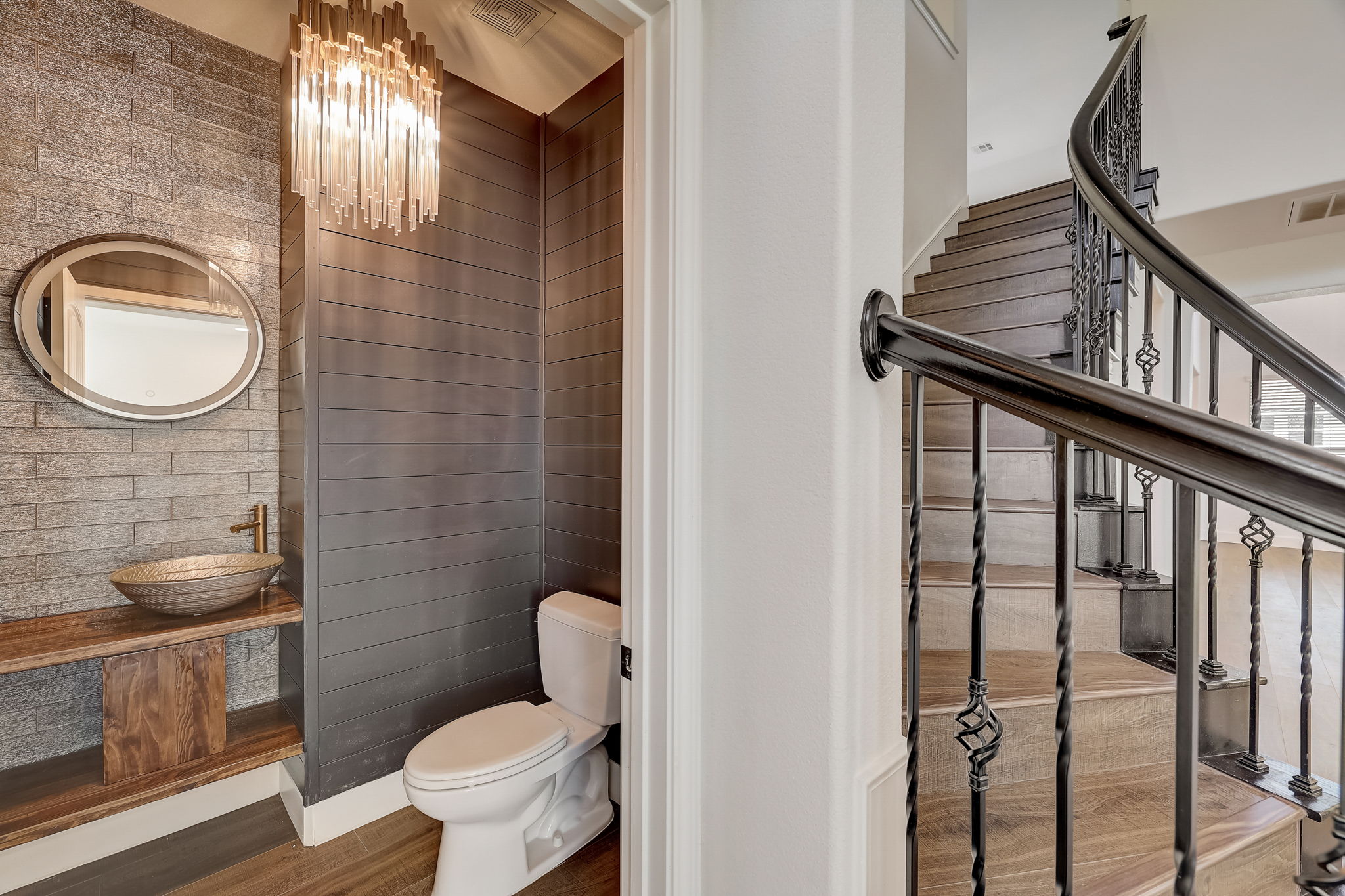 16012 Spillman Ranch Loop Austin, TX 78738 - Photo 19 of 38 Stylish powder room with vessel sink, plank accent walls, and elegant chandelier, conveniently located near a grand staircase.