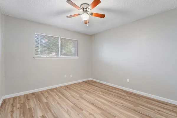 an empty room with a window and a ceiling fan