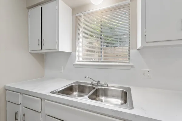a kitchen with granite countertop a sink and a white cabinets
