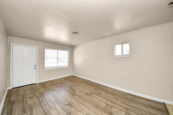 an empty room with wooden floor and windows